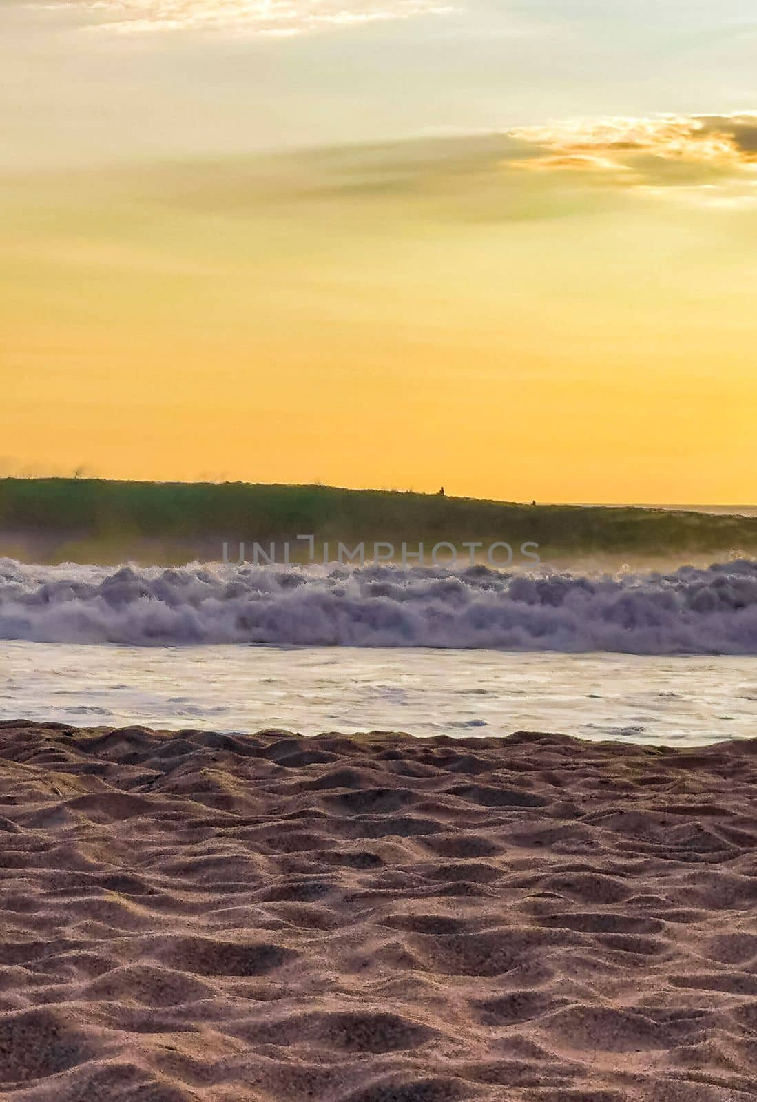 Beautiful stunning colorful and golden sunset in yellow orange red on beach and big wave panorama in tropical nature in Zicatela Puerto Escondido Oaxaca Mexico.