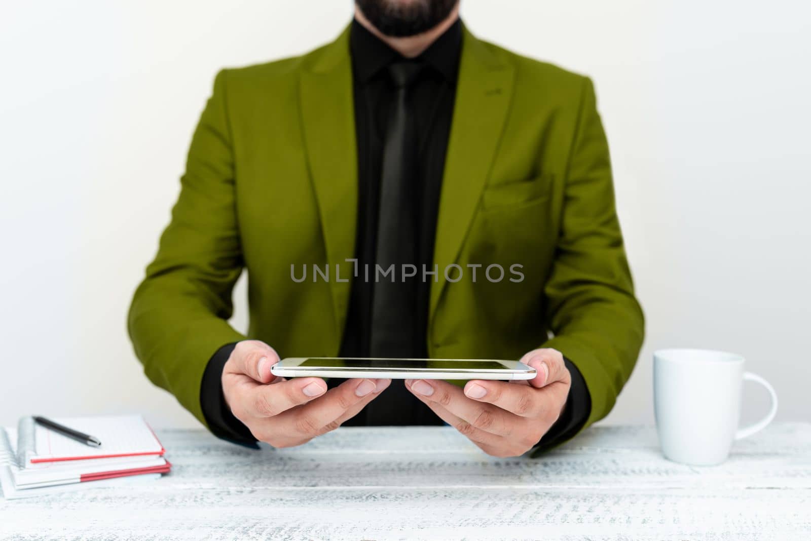 Businessman in Green jacket sitting at table and holding mobile phone. Presenting an important message. Executive In Suit Presenting Crutial Information. by nialowwa