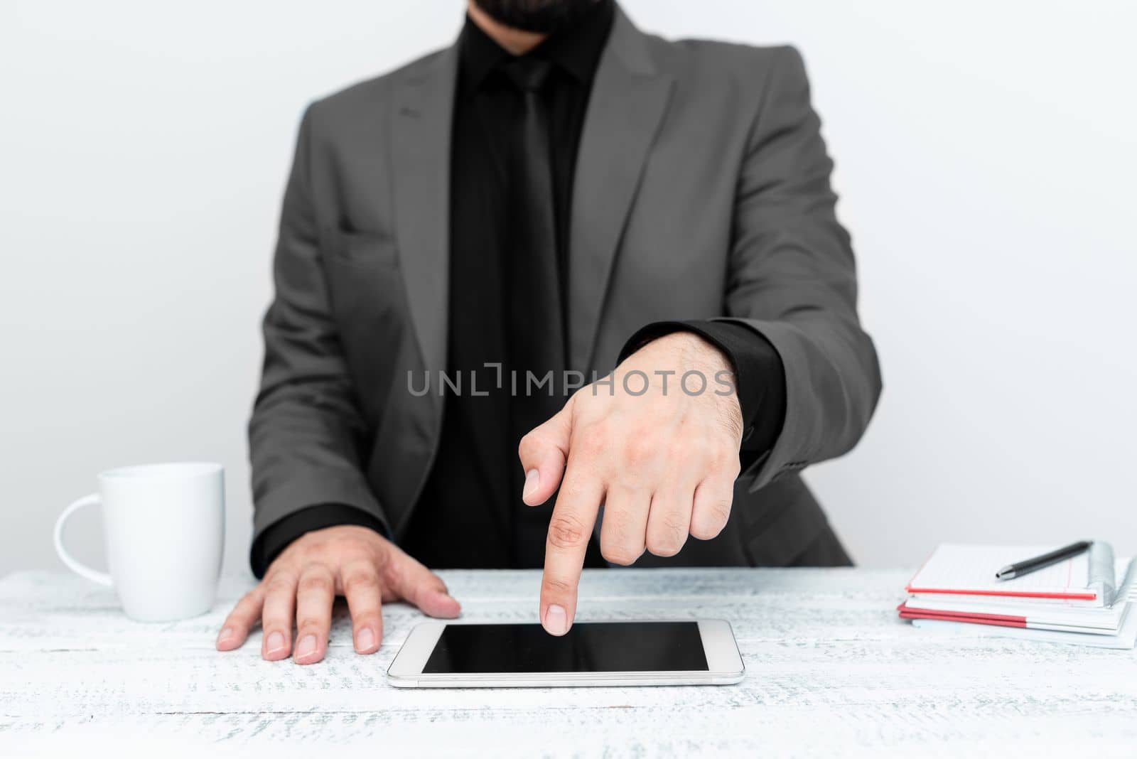Businessman in Gray jacket sitting at table And Pointing With One Finger On Important Message on the mobile phone. Gentleman Showing Critical Announcement. by nialowwa