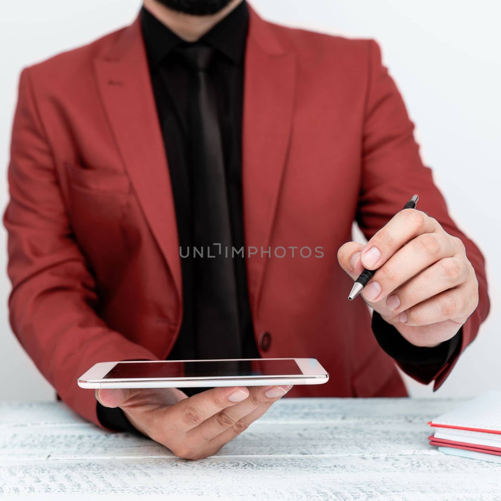 Man in jacket sitting at white table And Pointing With Pen On Message.