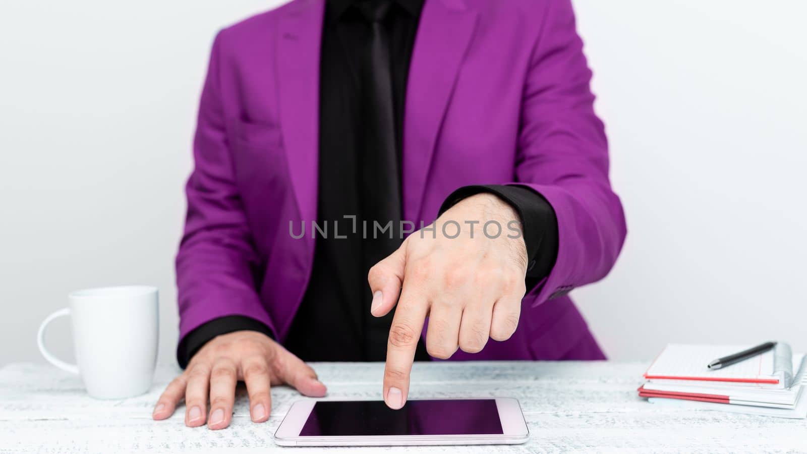 Businessman in Pink jacket sitting at table And Pointing With One Finger On Important Message on the mobile phone. Gentleman Showing Critical Announcement. by nialowwa