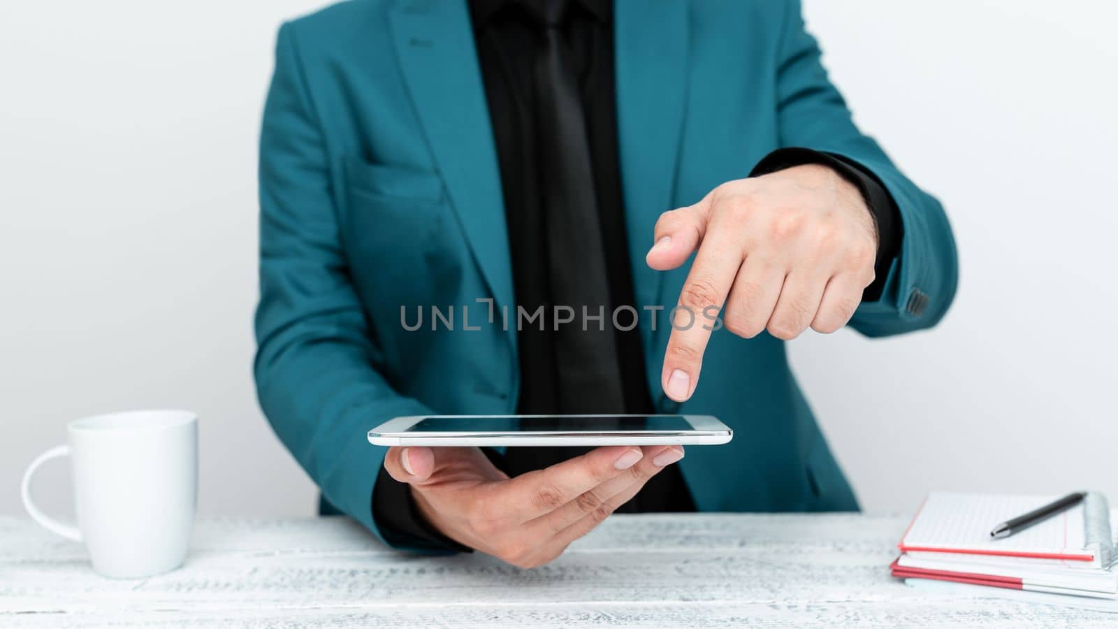 Businessman in Blue jacket sitting at table holding mobile phone And Pointing With One Finger On Important Message. Gentleman Showing Critical Announcement. by nialowwa