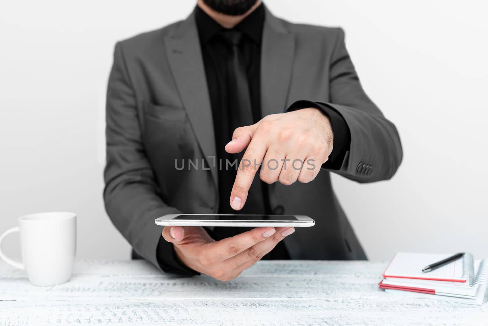 Businessman in a gray jacket sitting at a table holding a mobile phone
