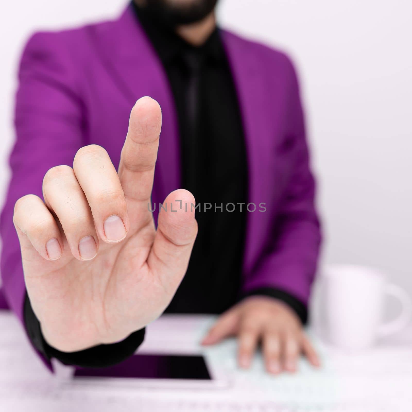 Businessman in a Pink jacket sitting at a table Phone on table.