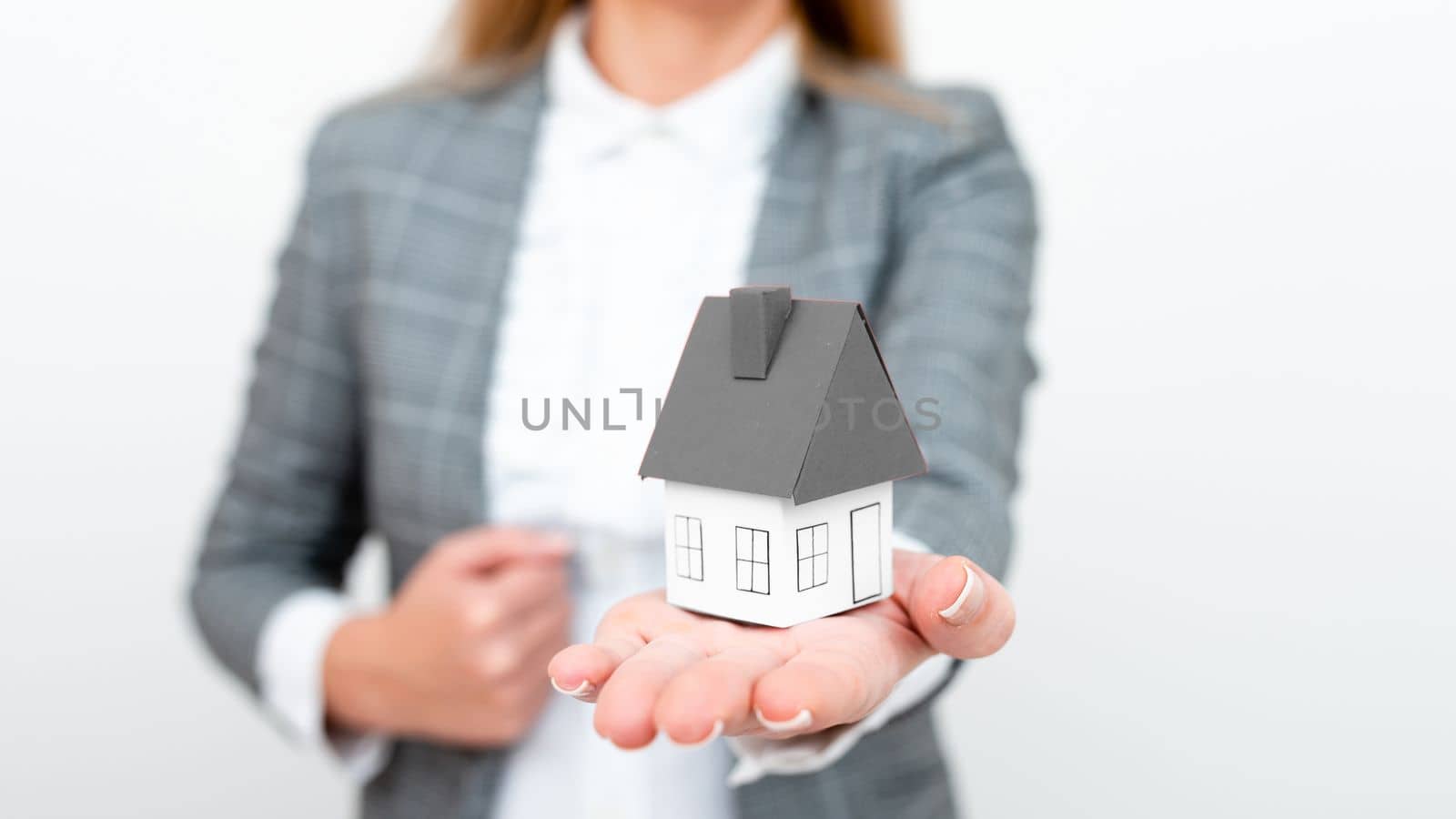 Businesswoman in gray suit holding colored paper house in one hand. Showing Important Informations. Executive Displaying Late News. Woman Showing Recent Updates. by nialowwa