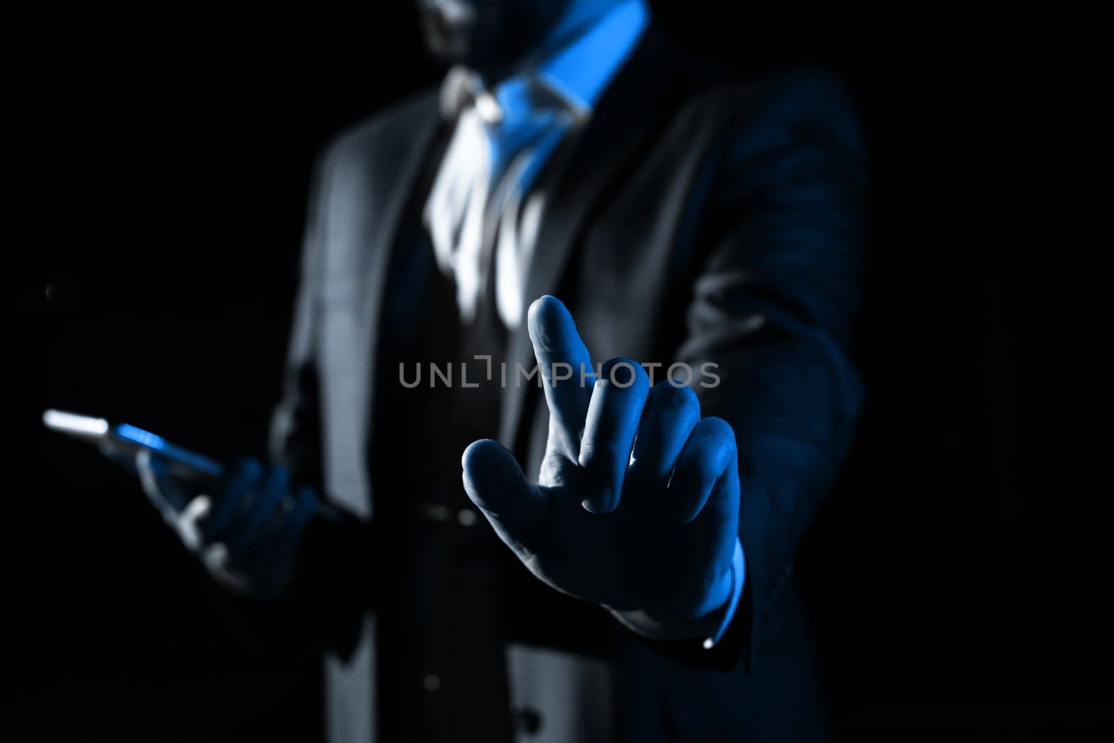 Man Holding Mobile Phone and Pointing On Recent Updates With One Finger. Businessman Having Virtual Reality Eyeglasses, Cellphone And Presenting New Idea. by nialowwa