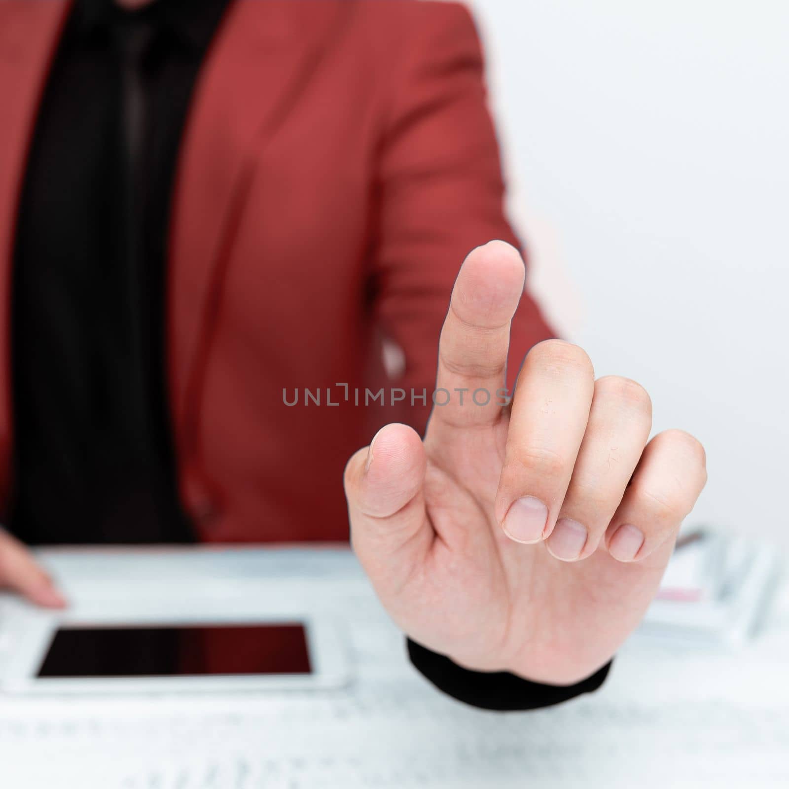 Businessman in Red jacket sitting at table And Pointing With One Finger On Important Message. Gentleman Showing Critical Announcement. Phone on table. by nialowwa