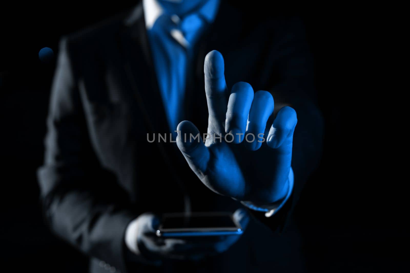 Man Holding Mobile Phone and Point On Recent Updates With One Finger. Businessman Having Virtual Reality Eyeglasses, Cellphone And Presenting New Idea. by nialowwa