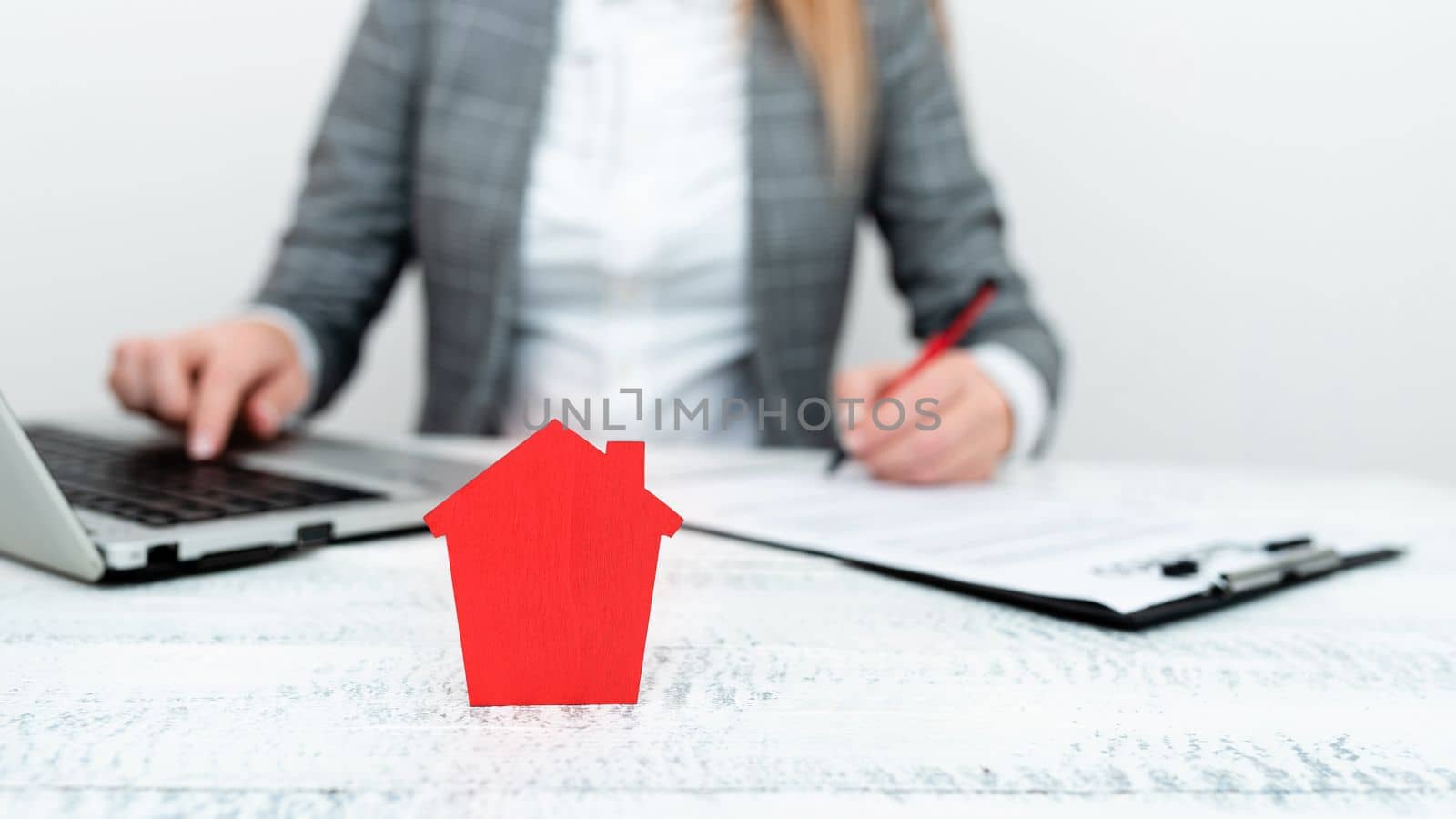 Businesswoman sitting at table writing in notebook and typing on laptop.