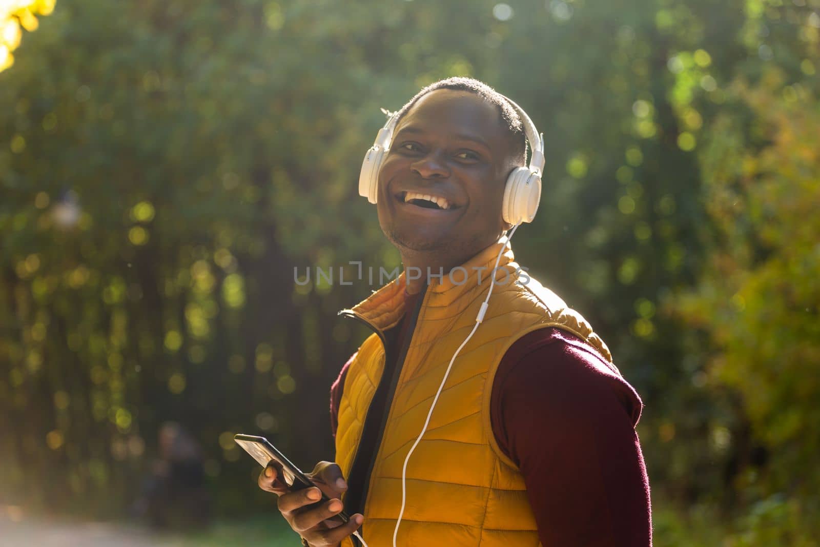 African american man listens music in autumn park copy space and place for advertising. Gadget, app and streaming service concept by Satura86