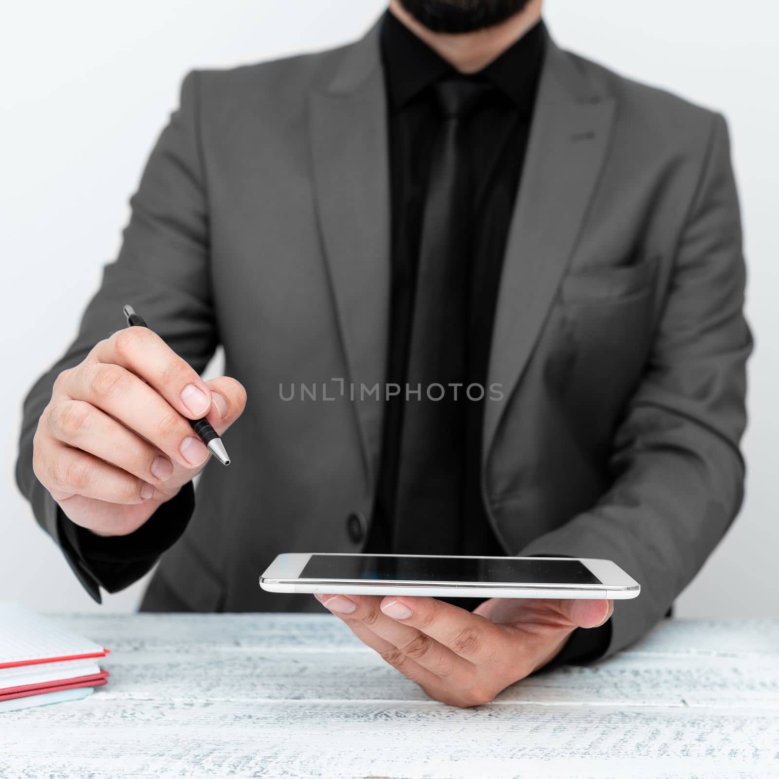 Man in jacket sitting at white table And Pointing With Pen On Message.