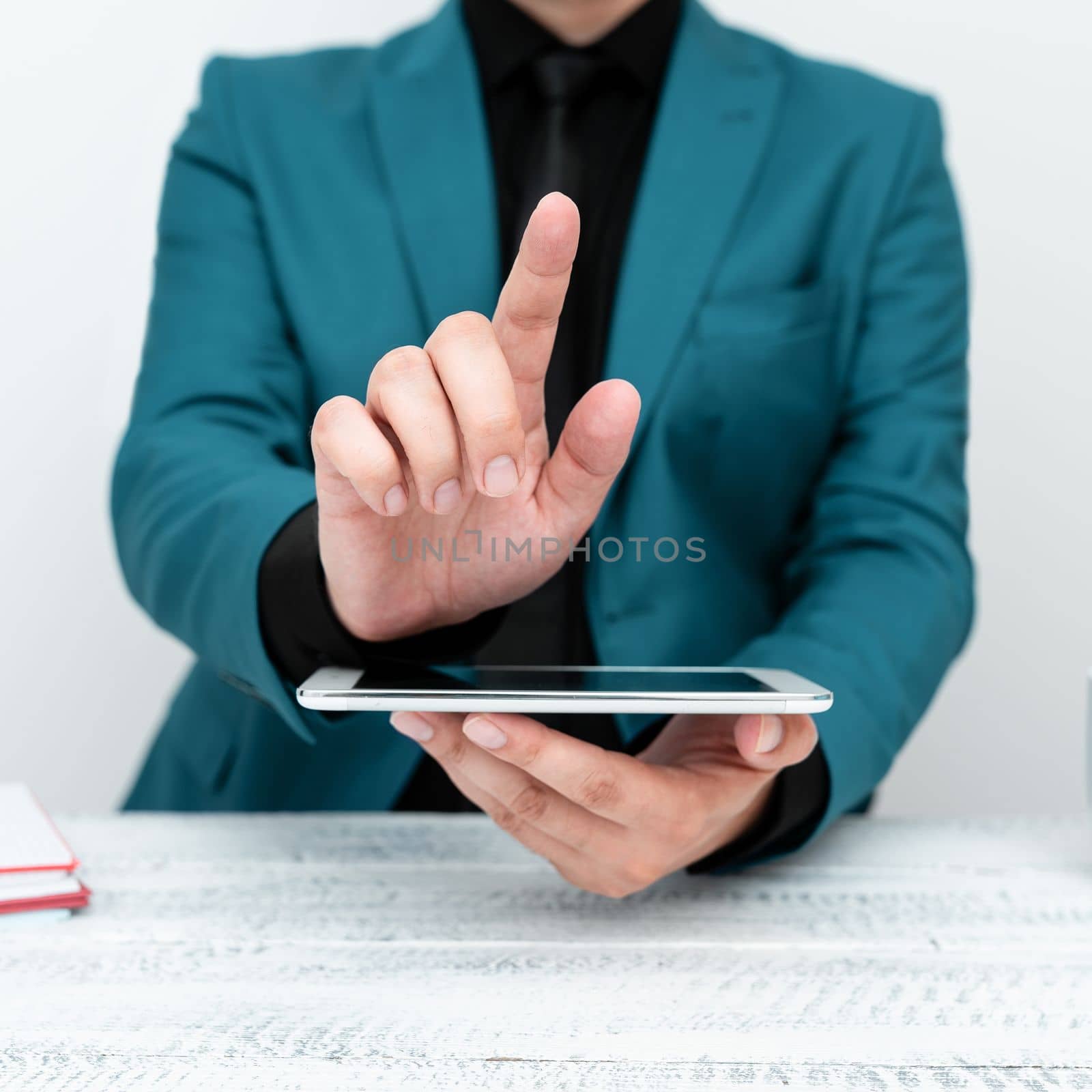 Businessman in a Blue jacket sitting at a table holding a mobile phone