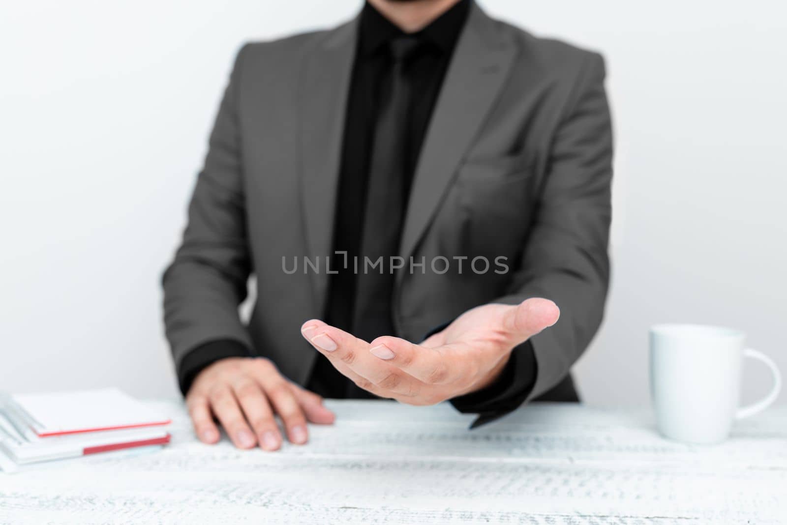 Businessman in Grey jacket Holding Important Message In One Hand. Man In Suit Showing New Crutial Idea In Palm. Executive Presenting Updated Critical Information. by nialowwa