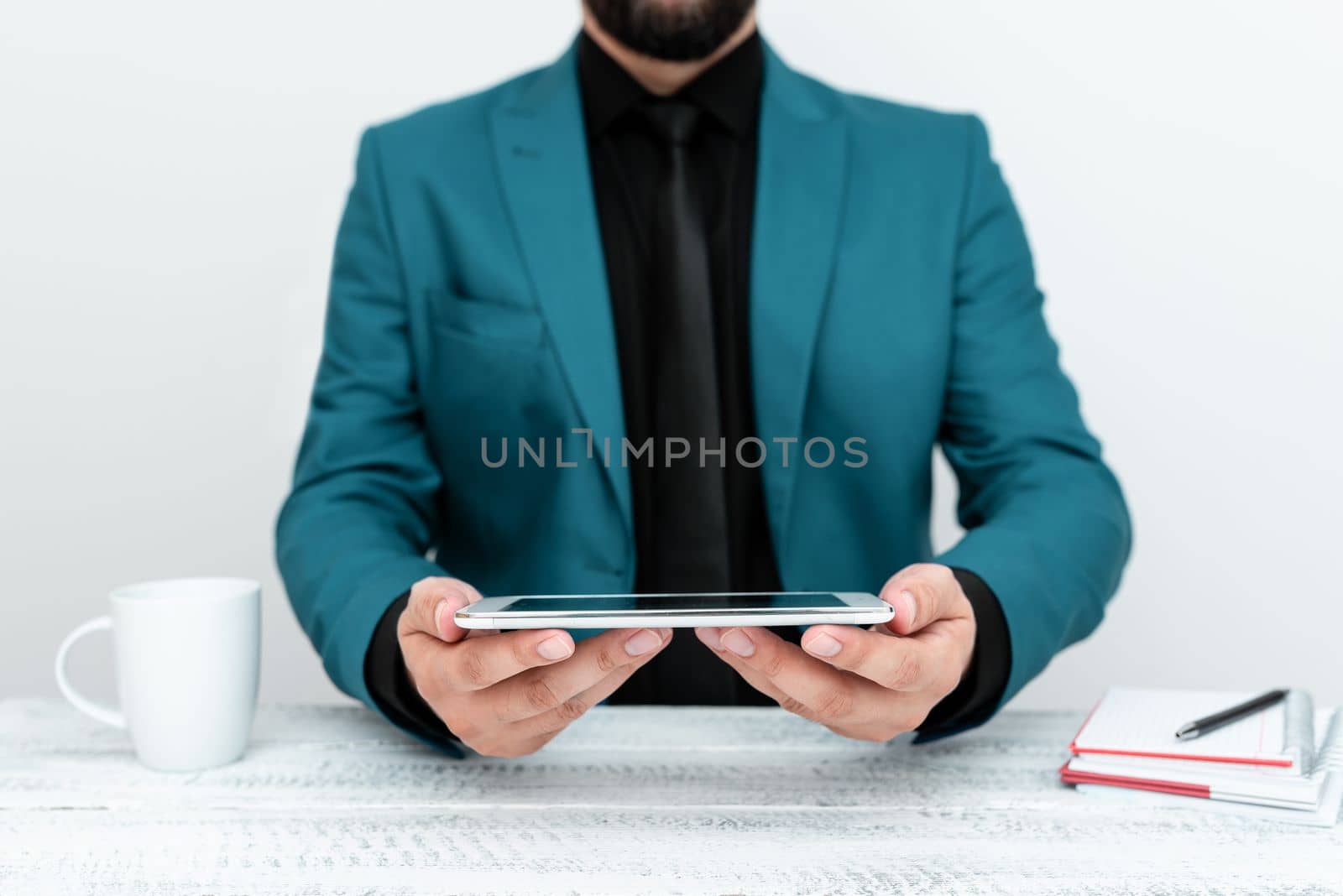 Businessman in Blue jacket sitting at a table and holding a mobile phone.