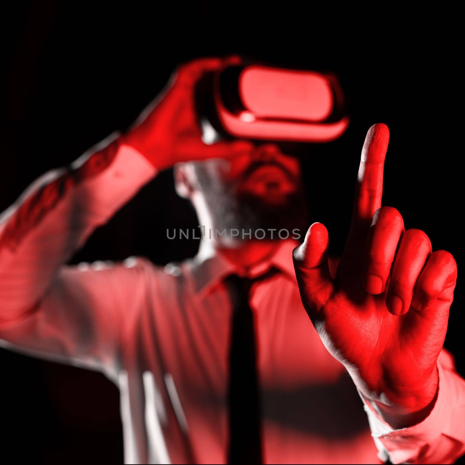 Man Wearing Vr Glasses And Pointing On Important Messages With One Finger. Businessman Having Virtual Reality Eyeglasses And Showing Crutial Informations. by nialowwa