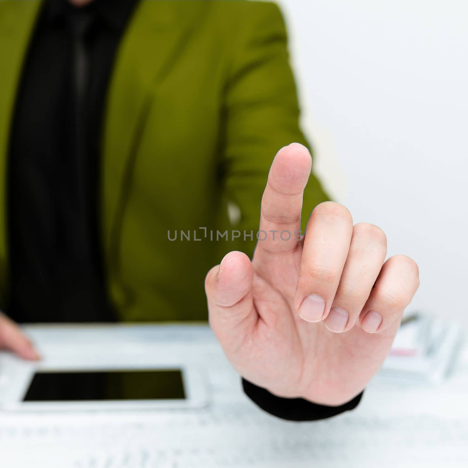 Businessman in Green jacket sitting at table And Pointing With One Finger On Important Message. Gentleman Showing Critical Announcement. Phone on table. by nialowwa