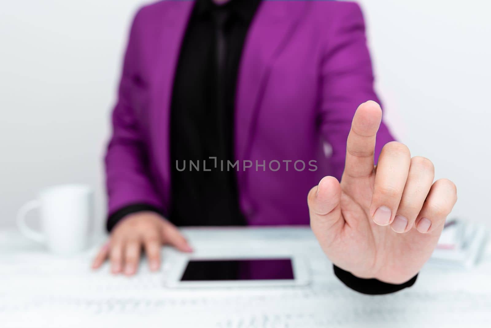 Businessman in Pink jacket sitting at table And Pointing With One Finger On Important Message. Gentleman Showing Critical Announcement. Phone on table. by nialowwa