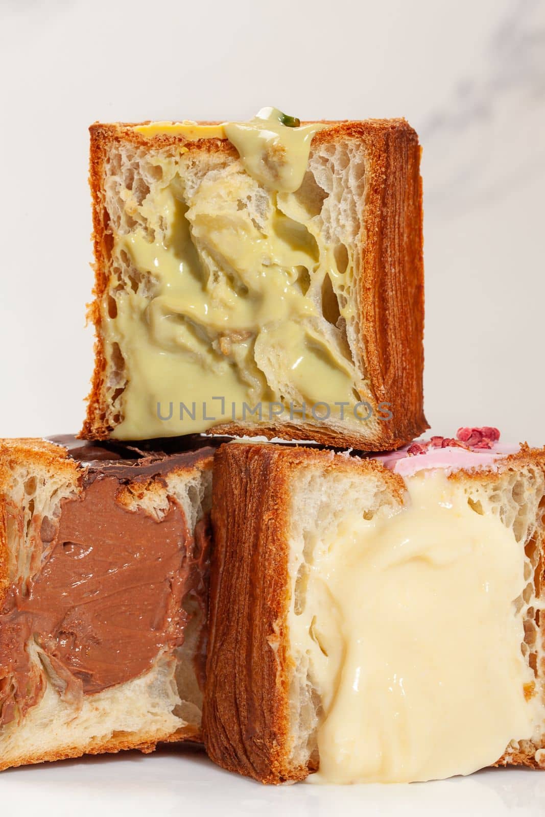 Pyramid of three halves of light, flaky and delicate croissants in forme of cubes with pistachio cream, vanilla custard and chocolate filling. Delicious sweet French style pastries