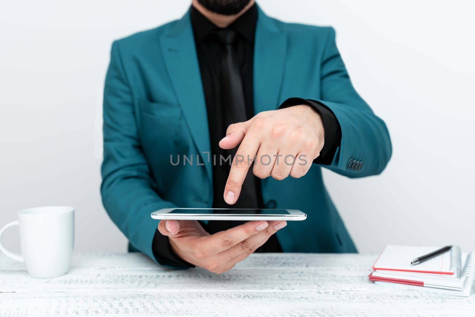 Businessman in a Blue jacket sitting at a table holding a mobile phone