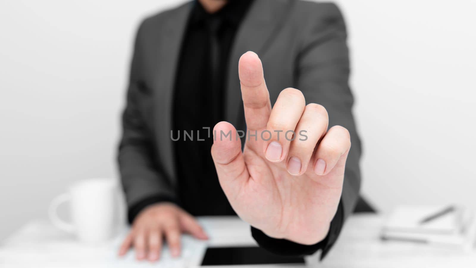 Businessman in Gray jacket sitting at table And Pointing With One Finger On Important Message. Gentleman Showing Critical Announcement. Phone on table. by nialowwa