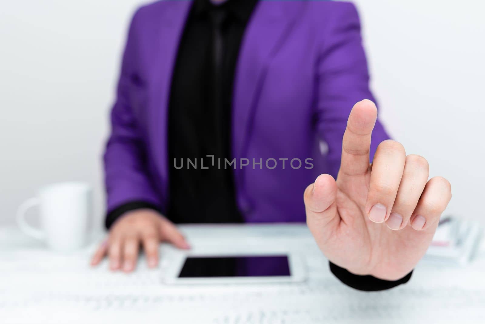 Businessman in Purple jacket sitting at table And Pointing With One Finger On Important Message. Gentleman Showing Critical Announcement. Phone on table. by nialowwa