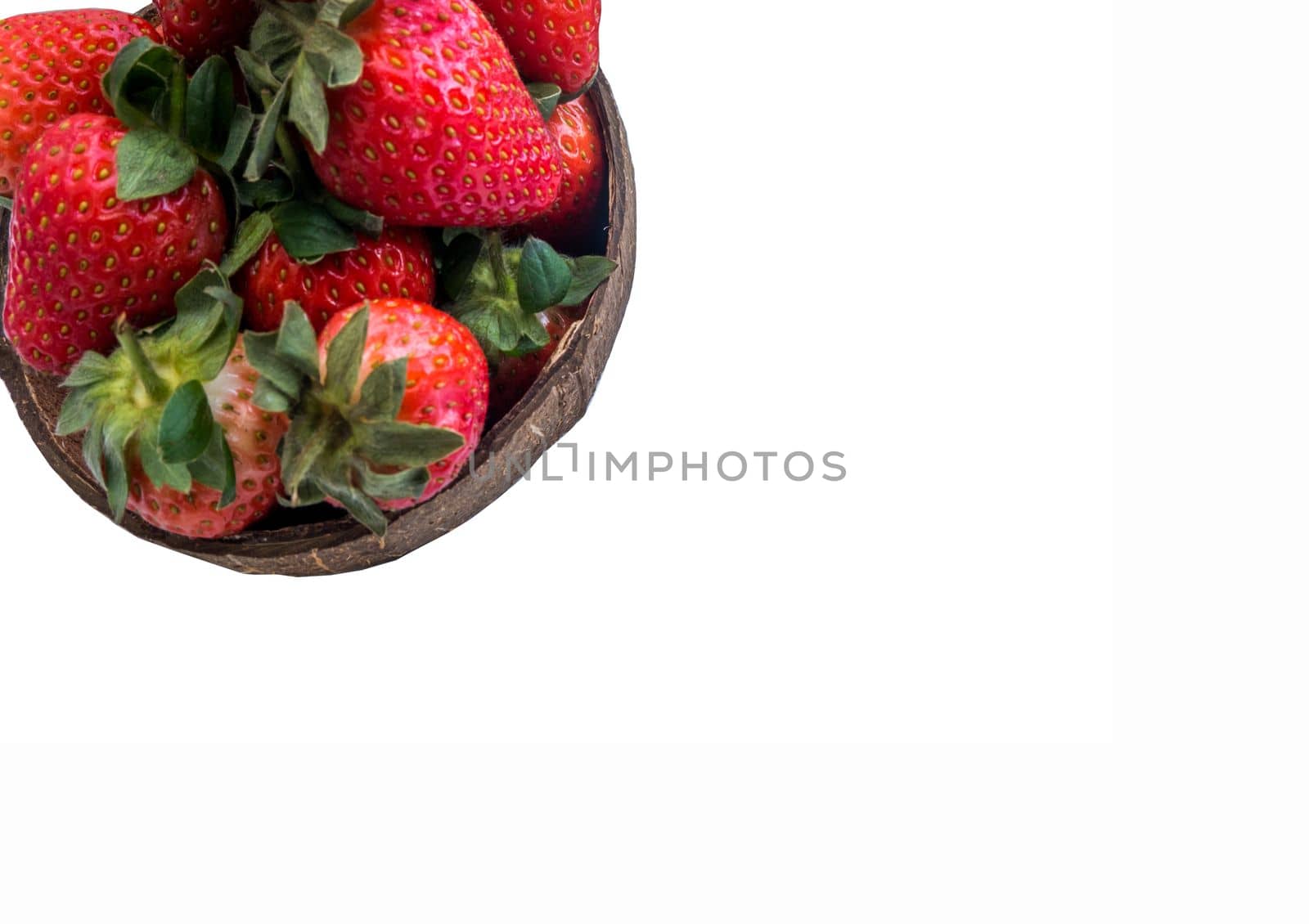 Fresh strawberries in a coconut shell on white background.