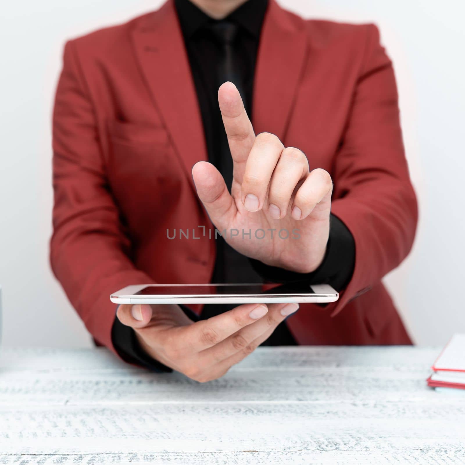 Businessman in a Red jacket sitting at a table holding a mobile phone