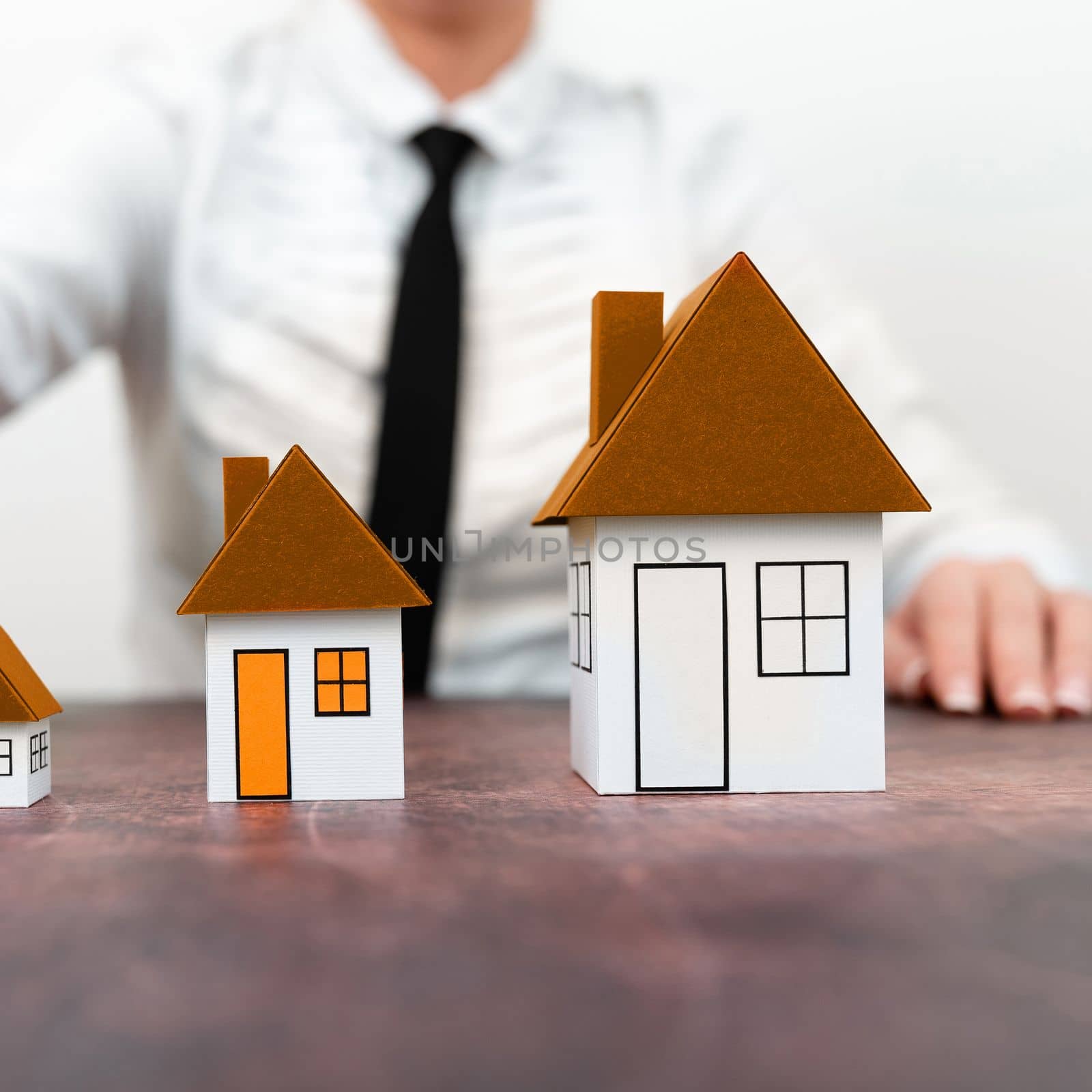 Businesswoman holding keys. olored paper houses standing on desk.