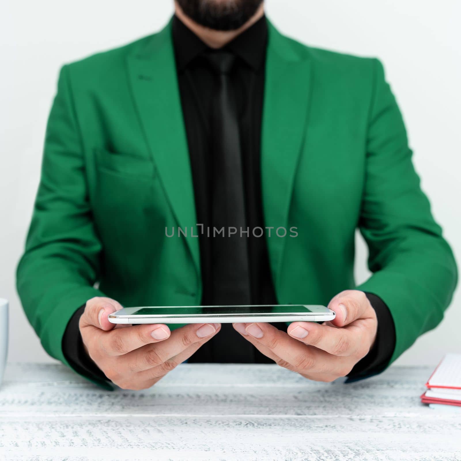 Businessman in Green jacket sitting at table and holding mobile phone. Presenting an important message. Executive In Suit Presenting Crutial Information. by nialowwa