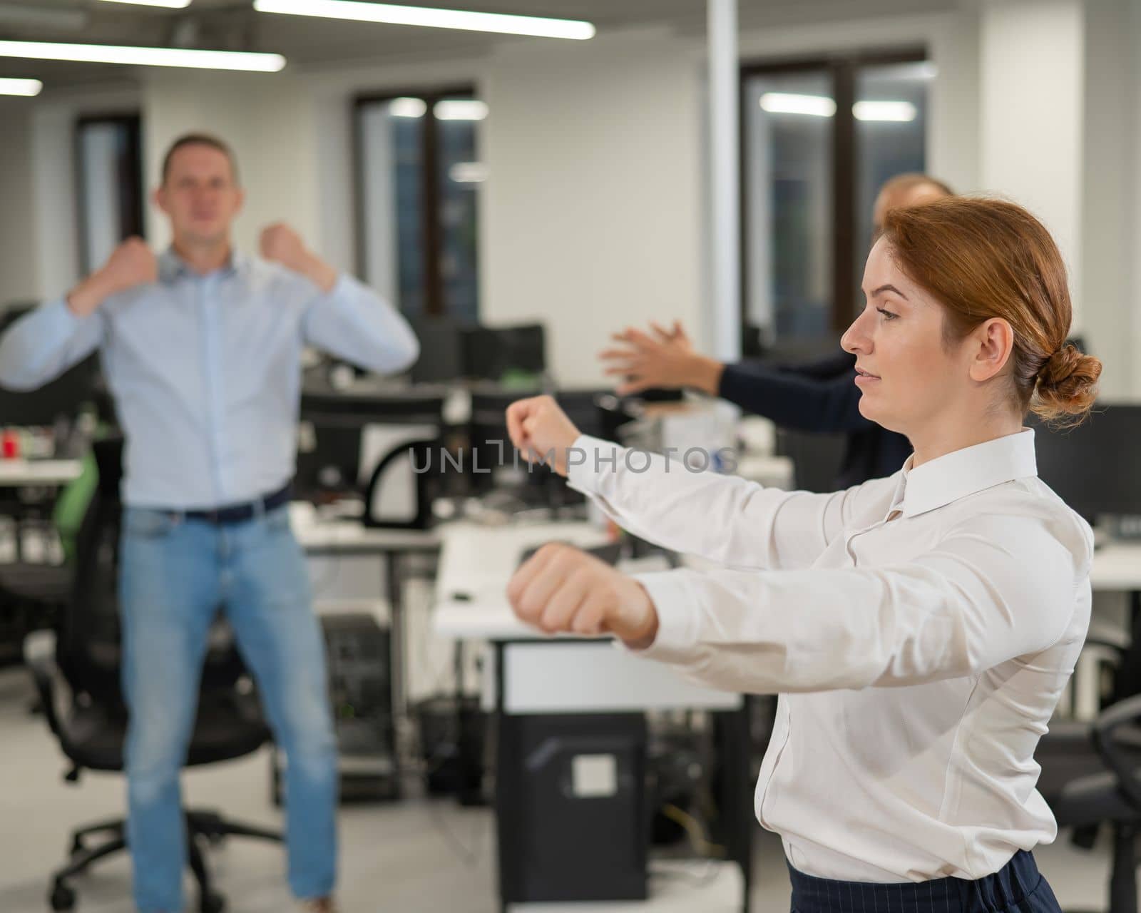 Three office workers warm up during a break. Employees do fitness exercises at the workplace