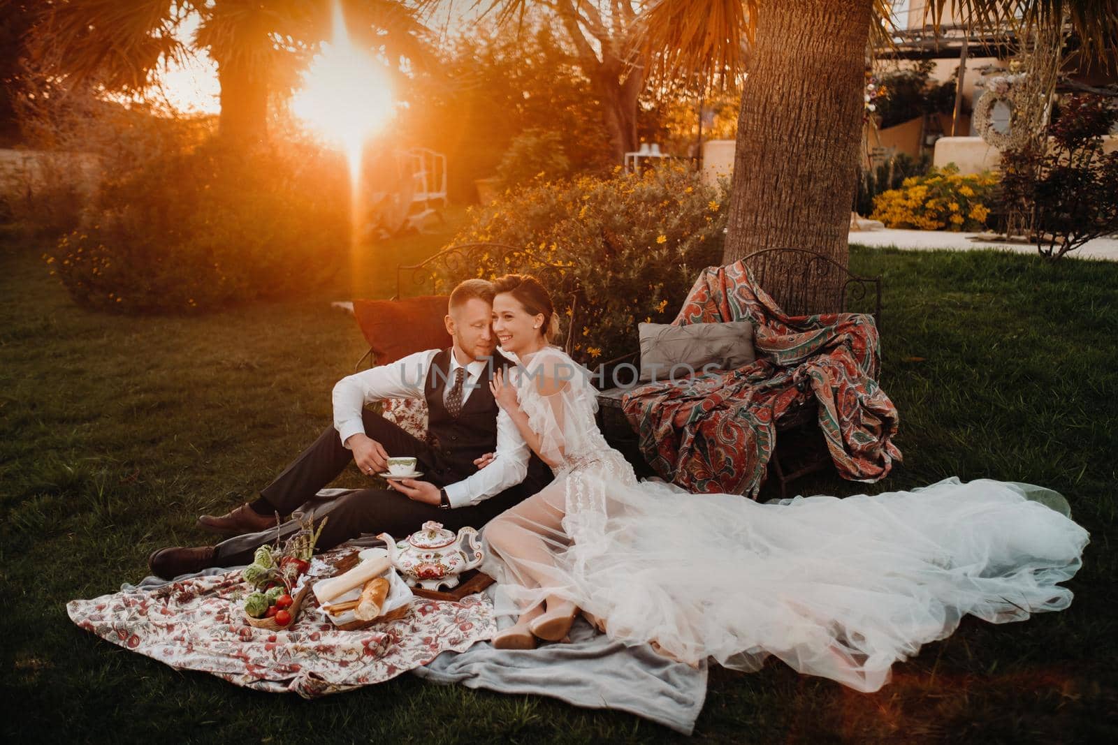 Dinner the Bridal couple at the picnic.A couple is relaxing at sunset in France.Bride and groom on a picnic in Provence. by Lobachad