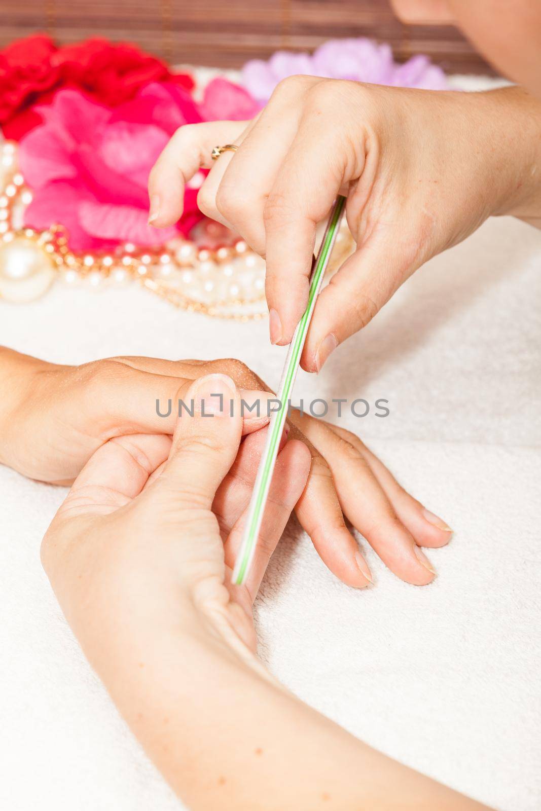 The beautician polish the client's nails before putting nail polish