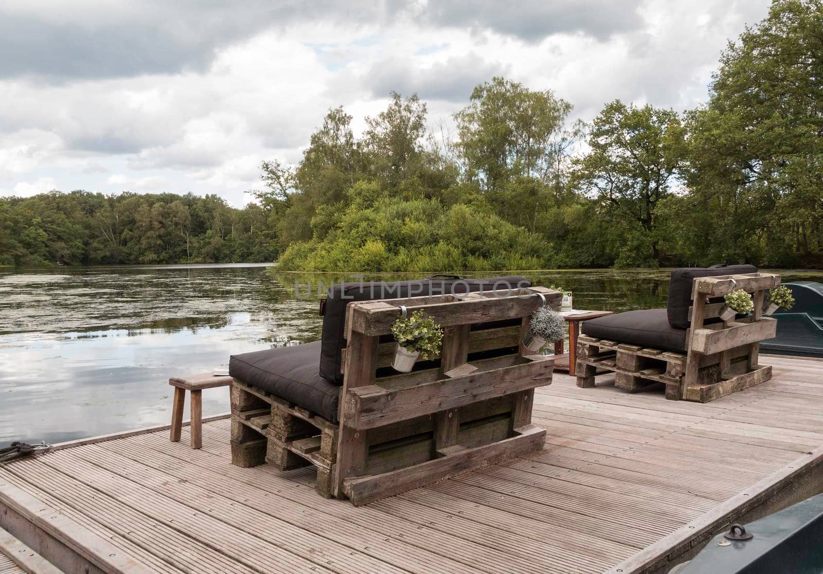 wooden benches made from old pallets with a view of a pond by compuinfoto