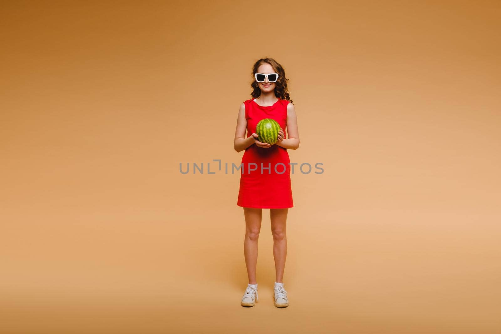 A beautiful girl in glasses and a red dress holds a watermelon in her hands by Lobachad