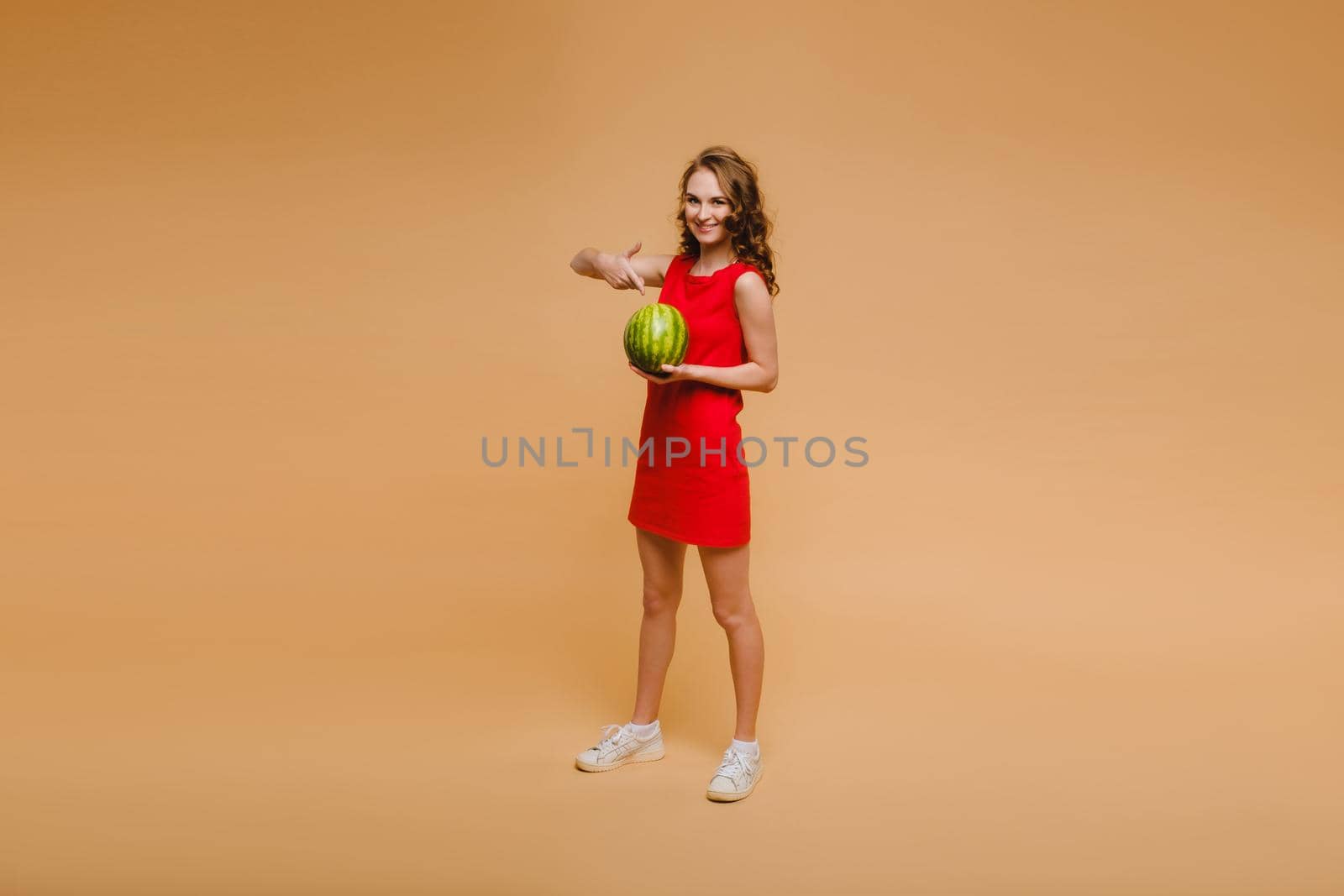 A beautiful girl in glasses and a red dress holds a watermelon in her hands by Lobachad