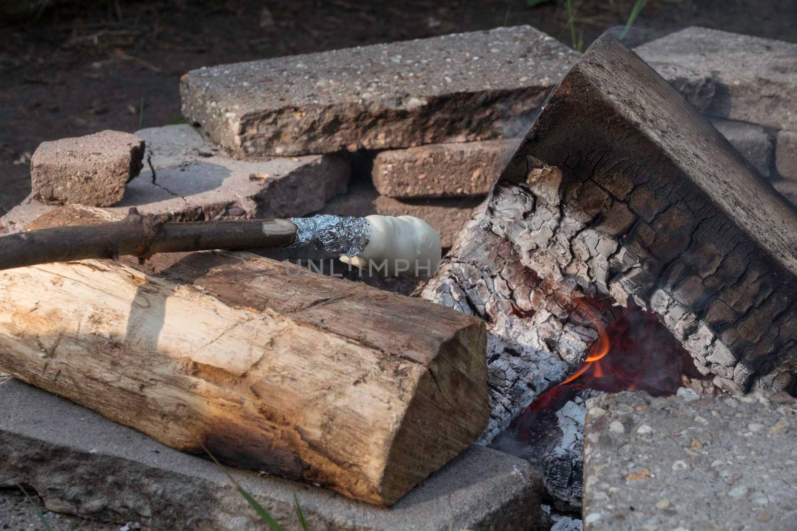 baking bread by heating bread dough on a stick over the campfire