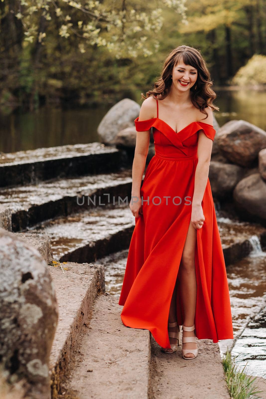 girl in a long red dress near the lake in the Park at sunset