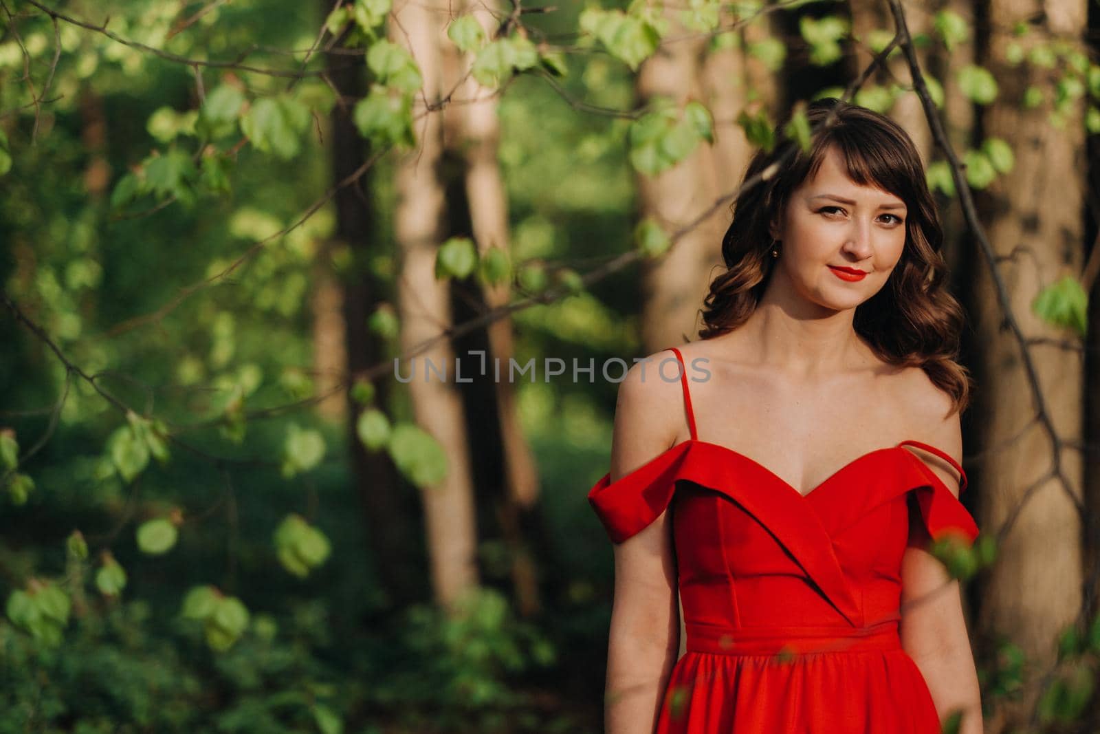 Spring Portrait of a laughing girl in a long red dress with long hair walking in the Park in the woods