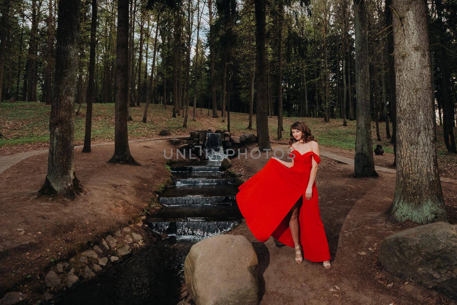 Spring Portrait of a laughing girl in a long red dress with long hair walking in the Park in the woods by Lobachad