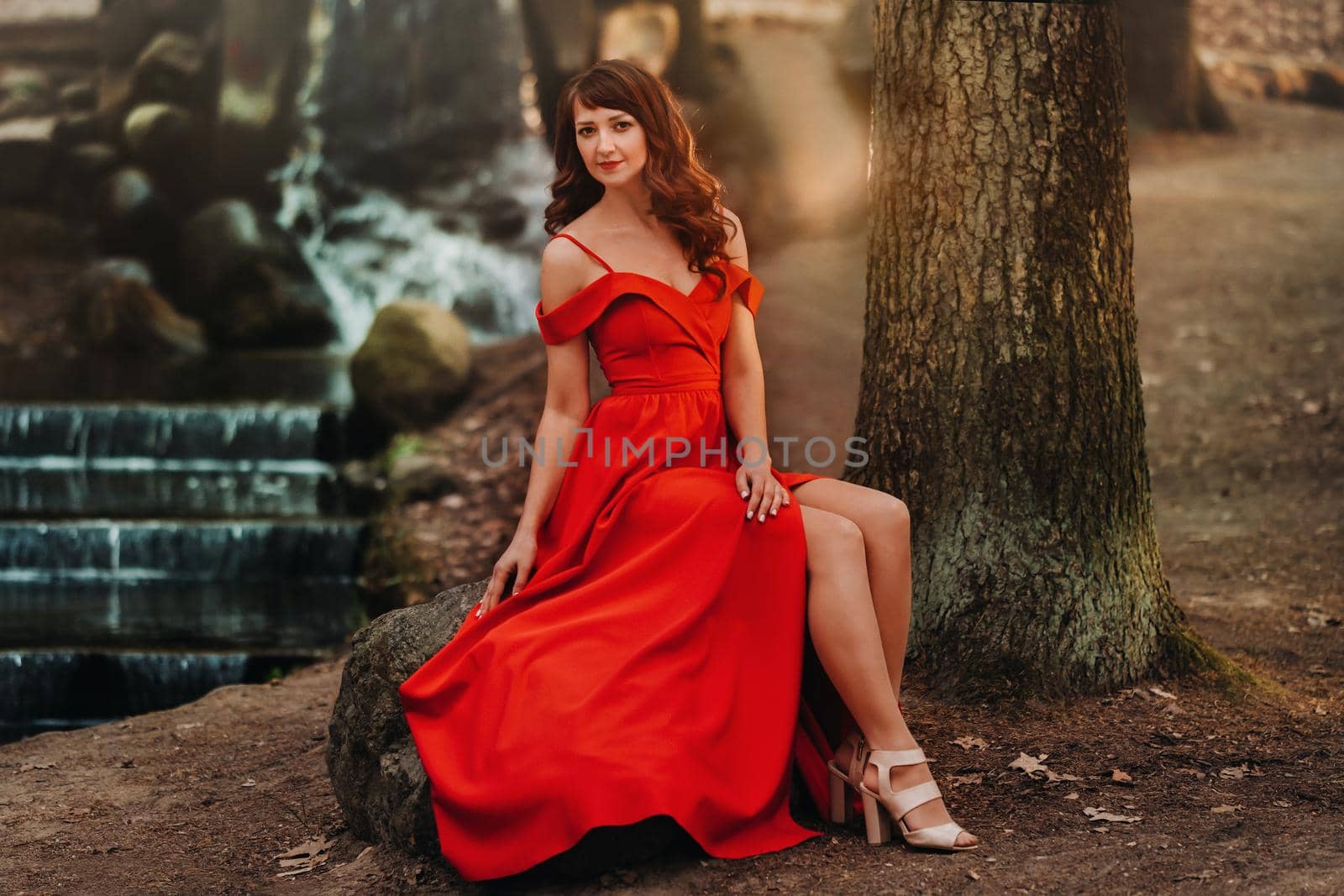 Spring Portrait of a laughing girl in a long red dress with long hair walking in the Park in the woods