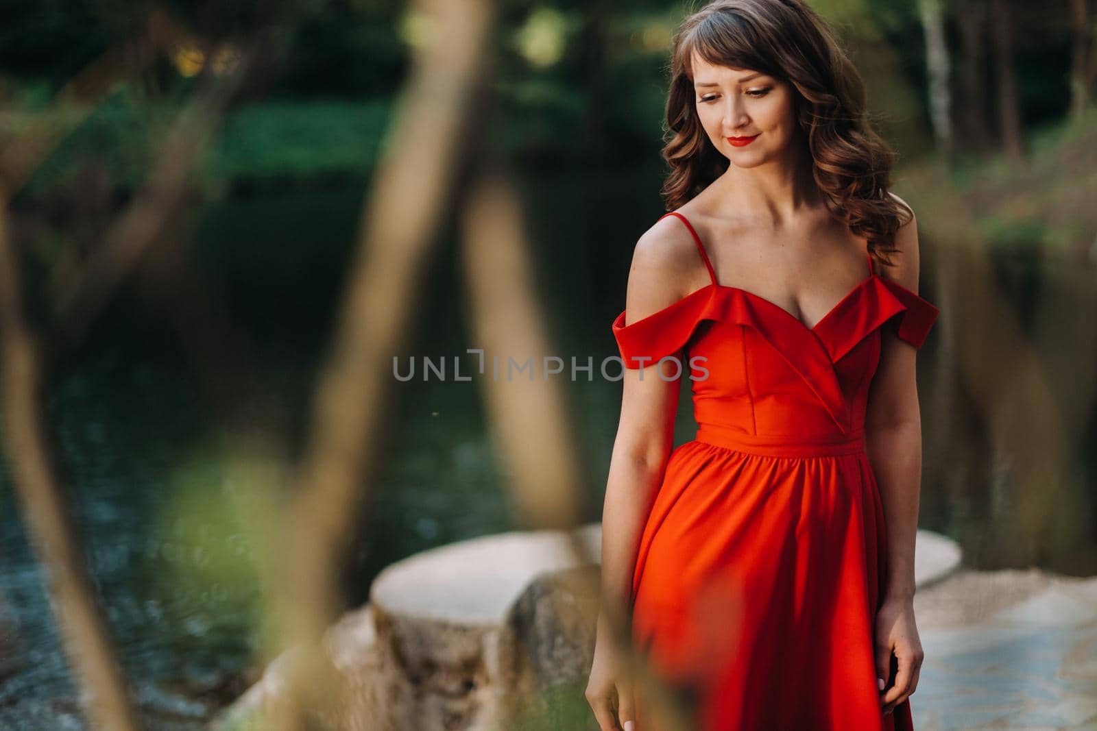 Spring Portrait of a laughing girl in a long red dress with long hair walking in the Park in the woods