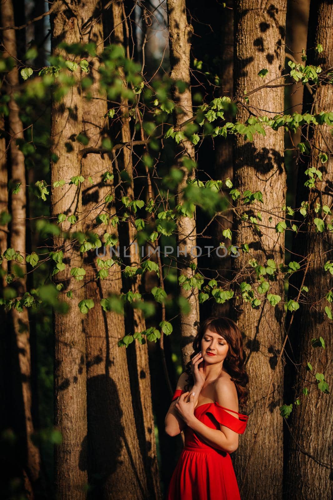 Spring Portrait of a laughing girl in a long red dress with long hair walking in the Park in the woods