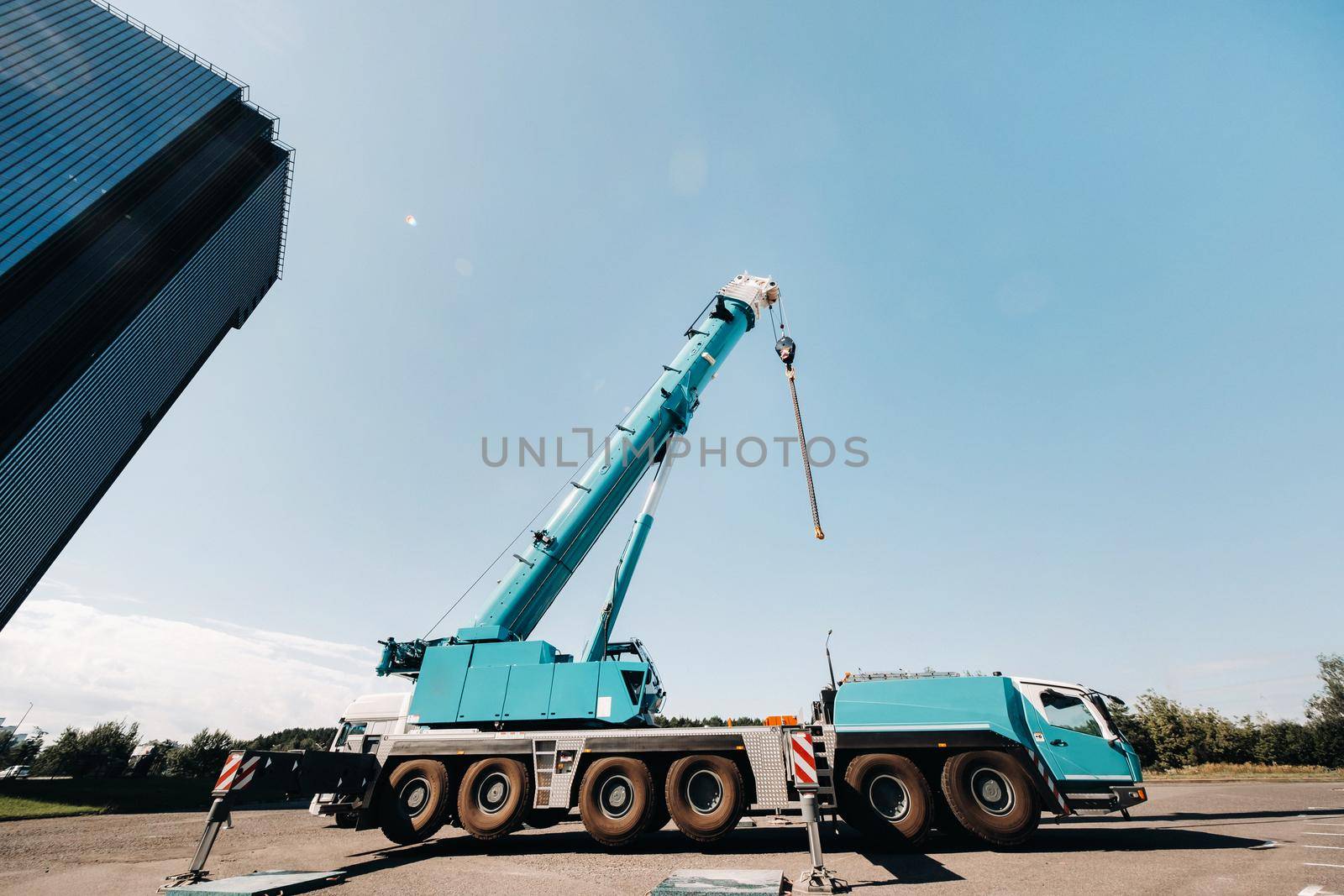 blue crane lifting mechanism with hooks near the glass modern building, crane and hydraulic high lift up to 120 meters.