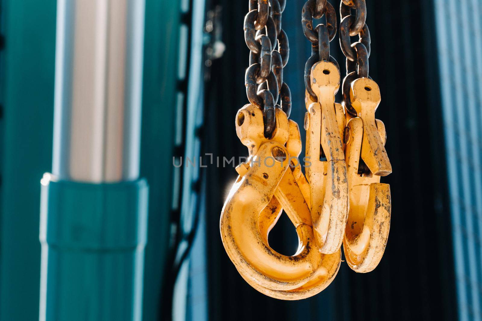 The hooks of the mobile crane near the glass of high buildings.Lots of hooks hanging from chains suspended from a crane by Lobachad