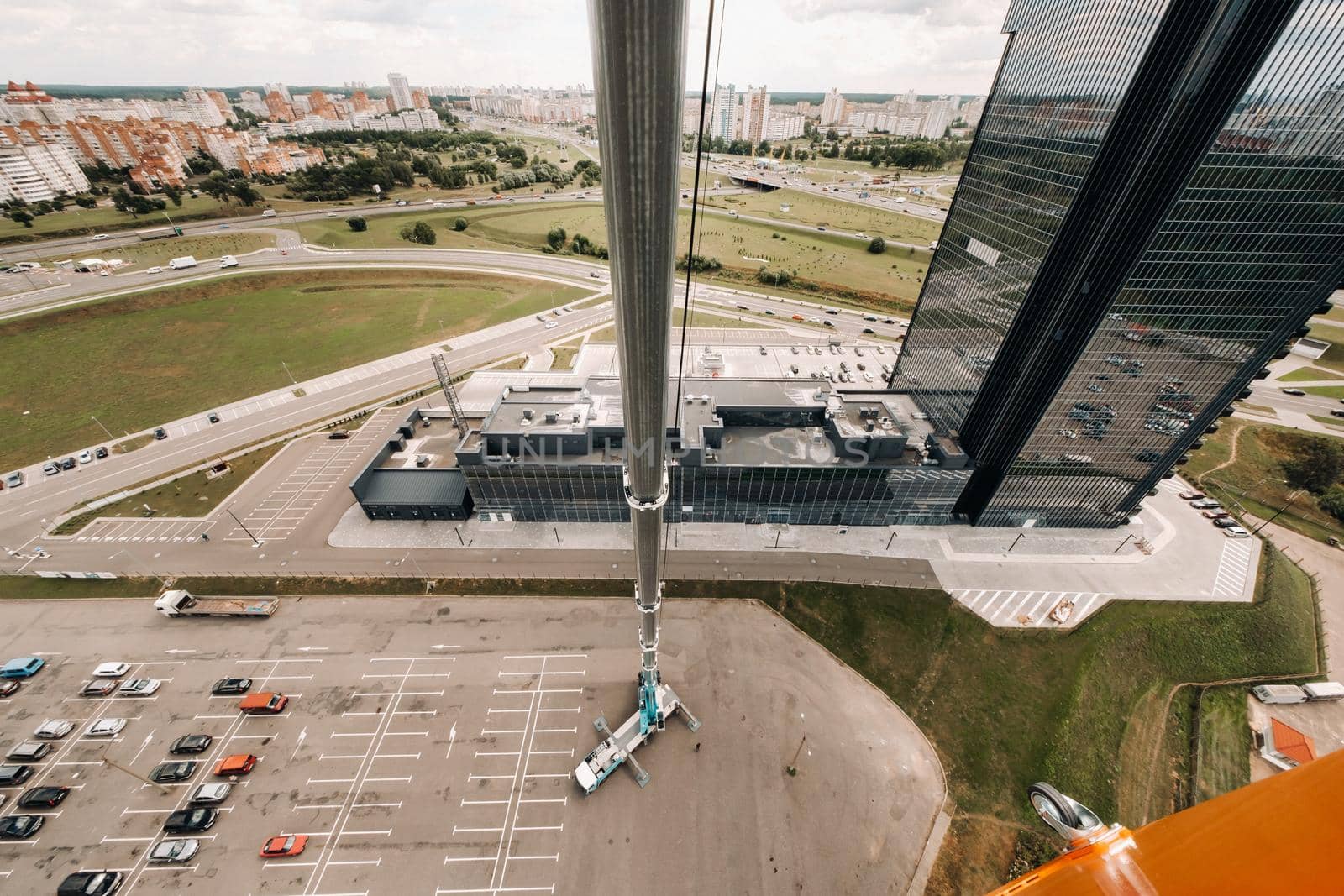 view from the height of the tallest car crane, which is open in the Parking lot near the glass building in the city and ready to work. the highest mobile crane is deployed on the site. the height of the arrow is 80 meters