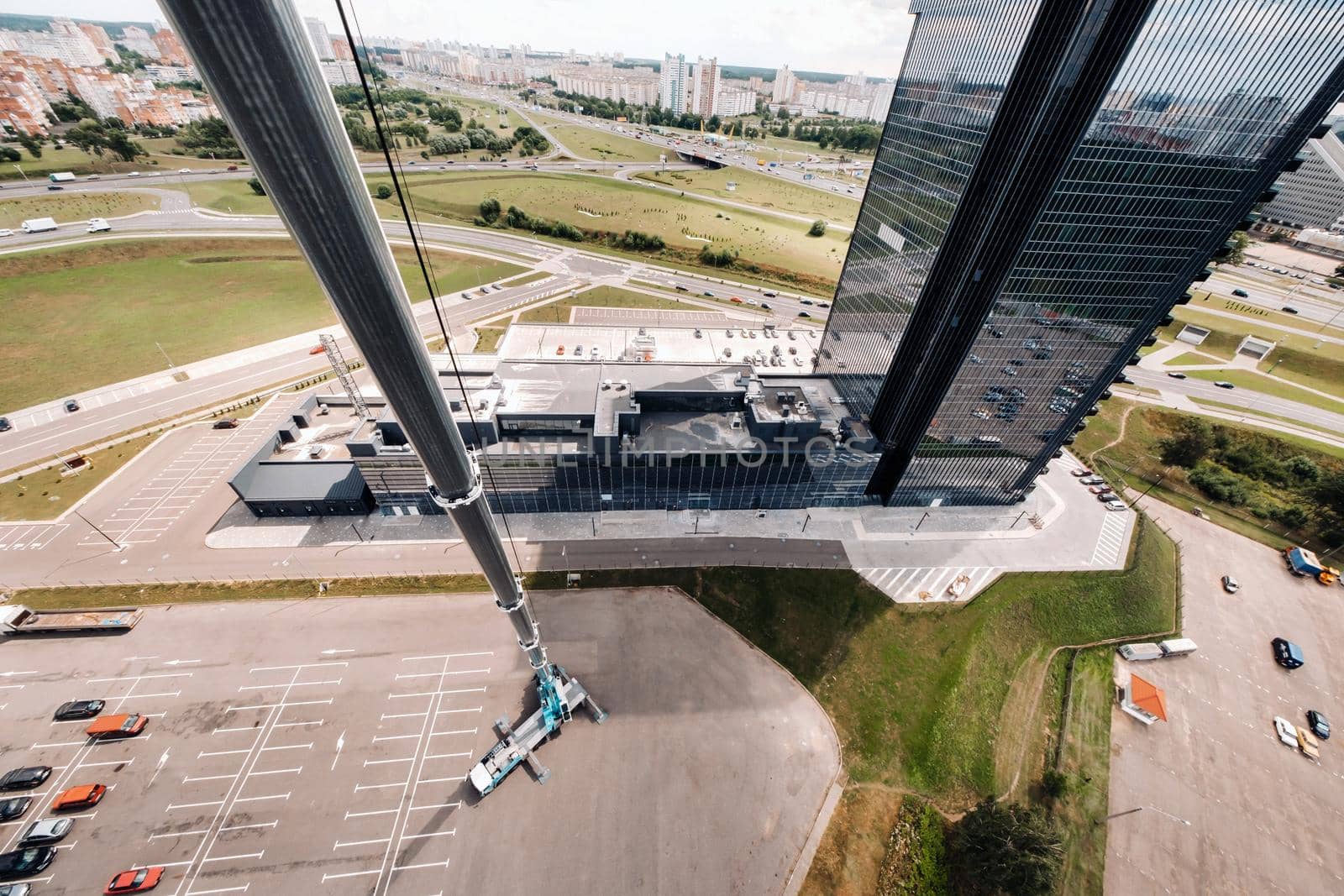 view from the height of the tallest car crane, which is open in the Parking lot near the glass building in the city and ready to work. the highest mobile crane is deployed on the site. the height of the arrow is 80 meters