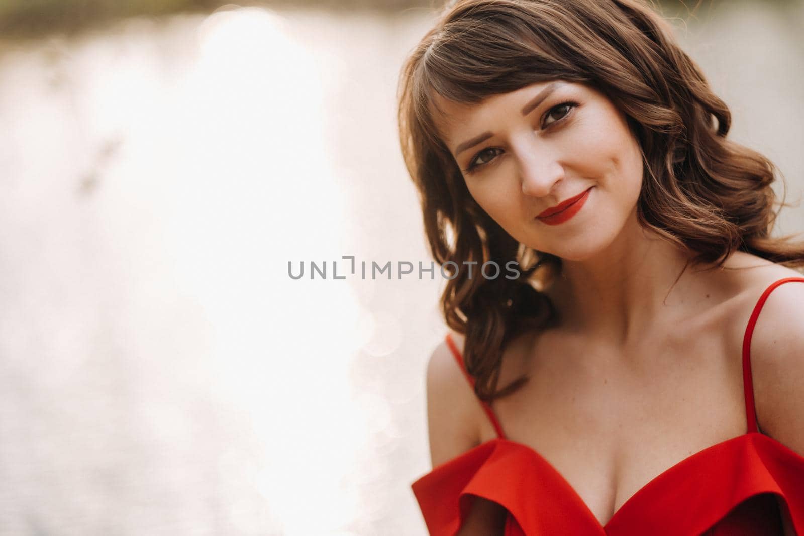 Spring Portrait of a laughing girl in a long red dress with long hair walking in the Park in the woods