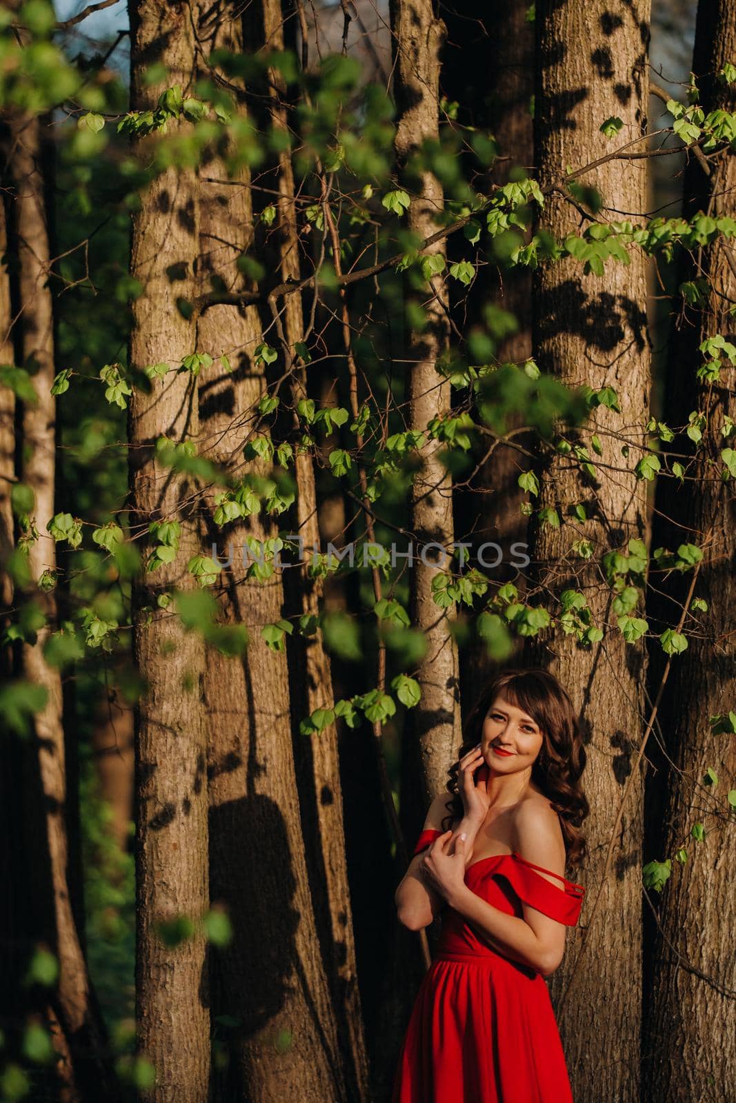 Spring Portrait of a laughing girl in a long red dress with long hair walking in the Park in the woods