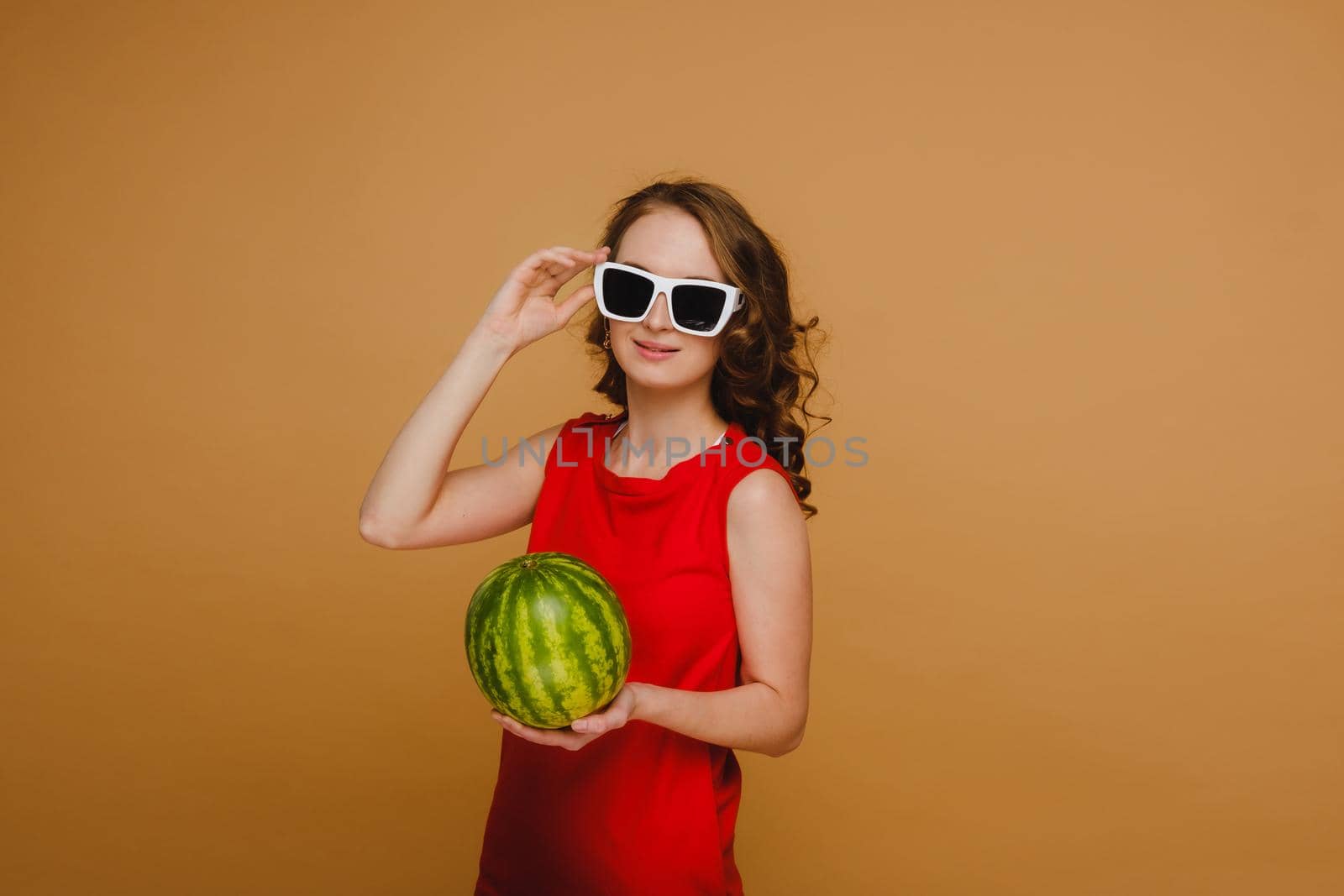 A beautiful girl in glasses and a red dress holds a watermelon in her hands by Lobachad