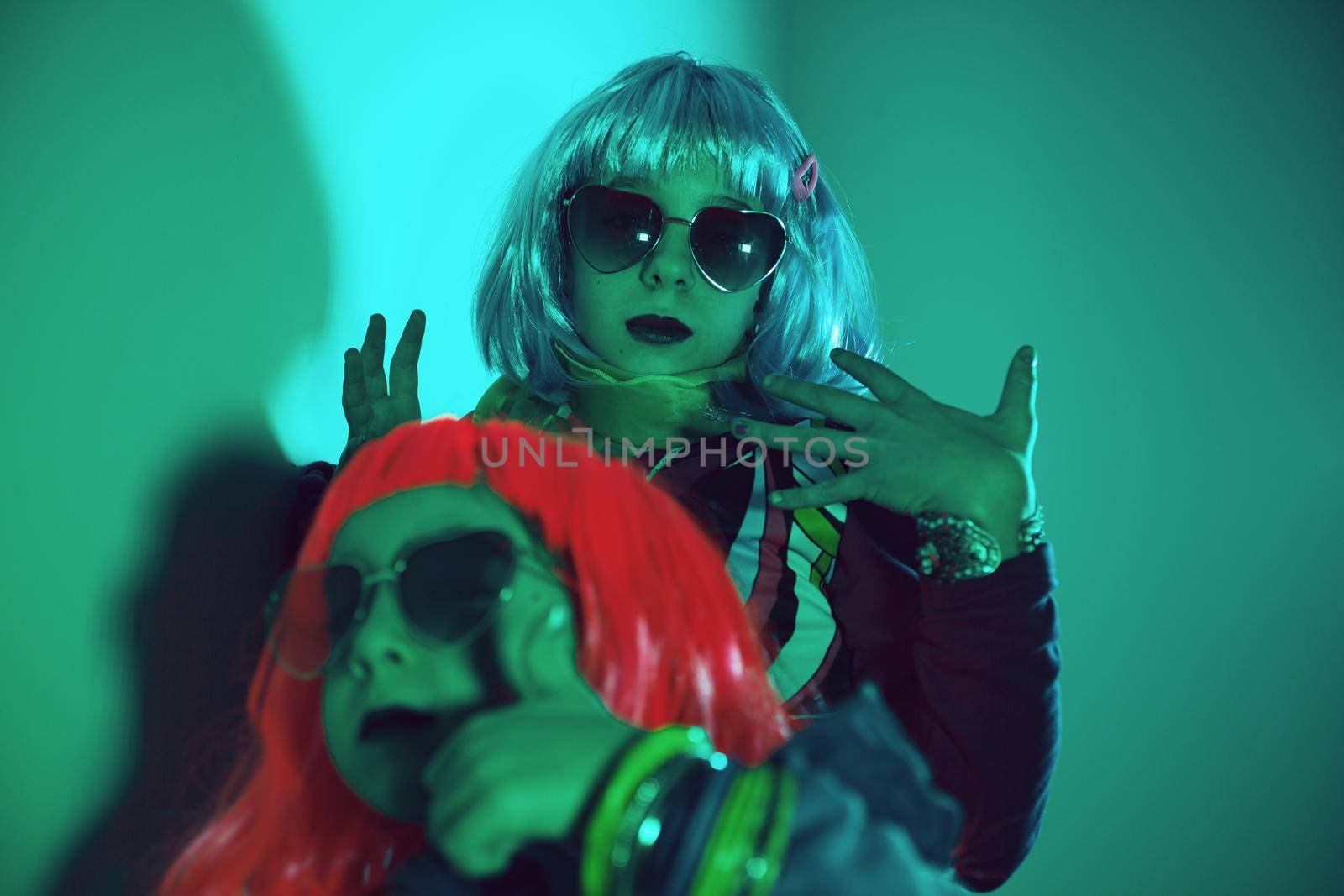 Little girls wearing a colorful wig and heart-shaped sunglasses posed for a photo shooting on the disco light background